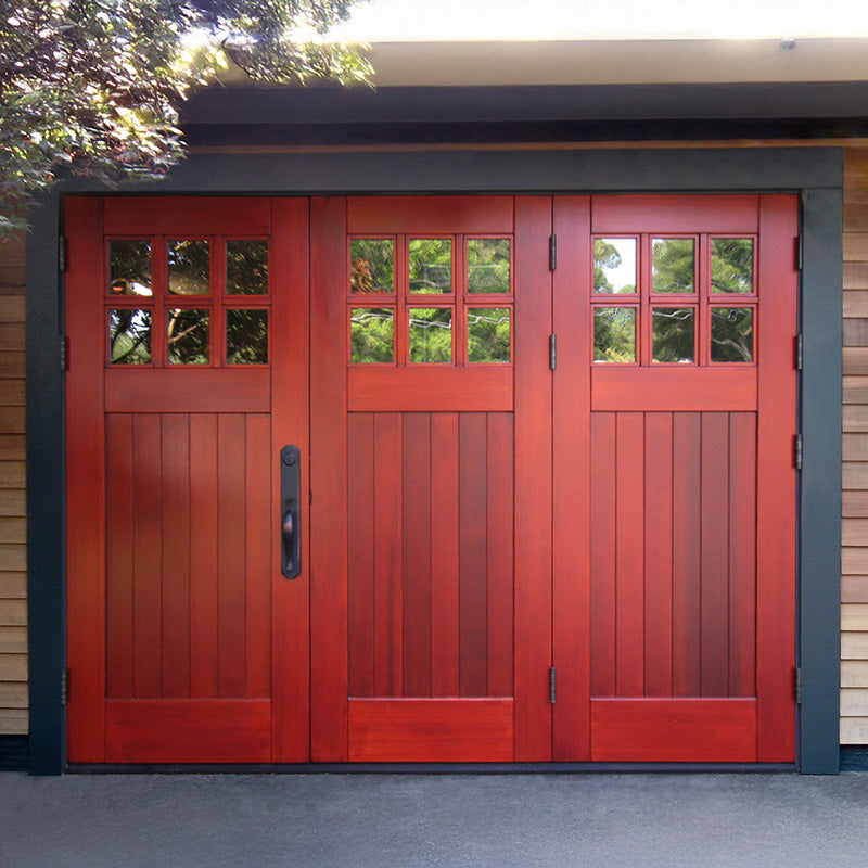Deep red folding garage doors with vertical paneling and divided glass windows, creating a bold, architectural focal point within a clean, modern exterior.