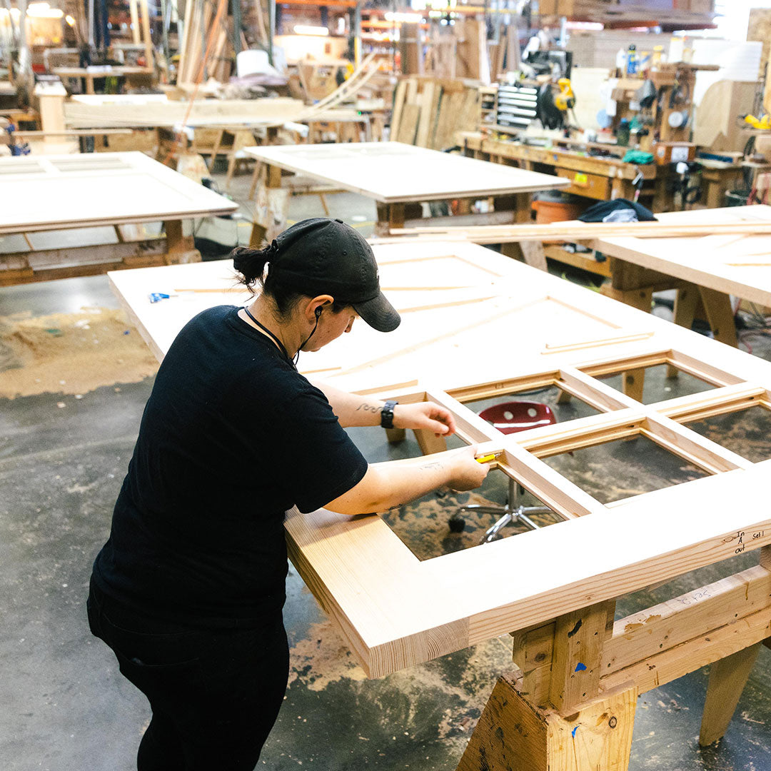 Craftswoman adding glass panes windows to a carriage door