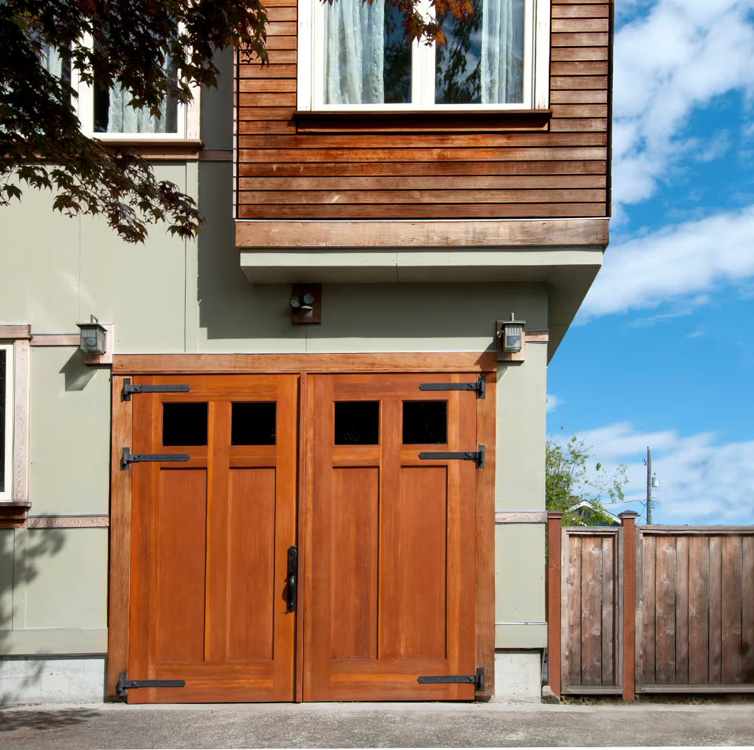 Craftsman-style carriage garage door with two glass panels, installed on a residential exterior in natural daylight.
